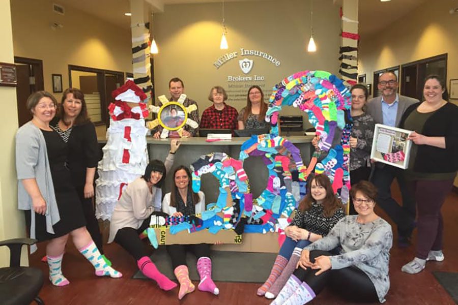 Community Involvement - Portrait of Miller Insurance Team in the Office Donating Socks