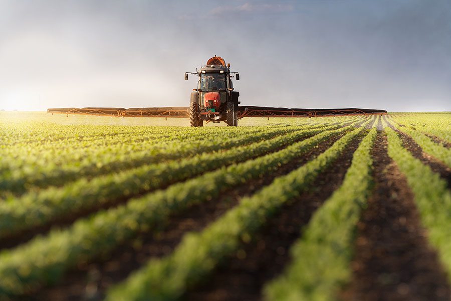 Specialized Business Insurance - View of Tractor Fertilizing Field of Crops on a Farm